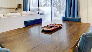Une table à manger avec un plateau en bois et un bol, entourée de chaises à l  ’assise rembourrée de tissu bleu.