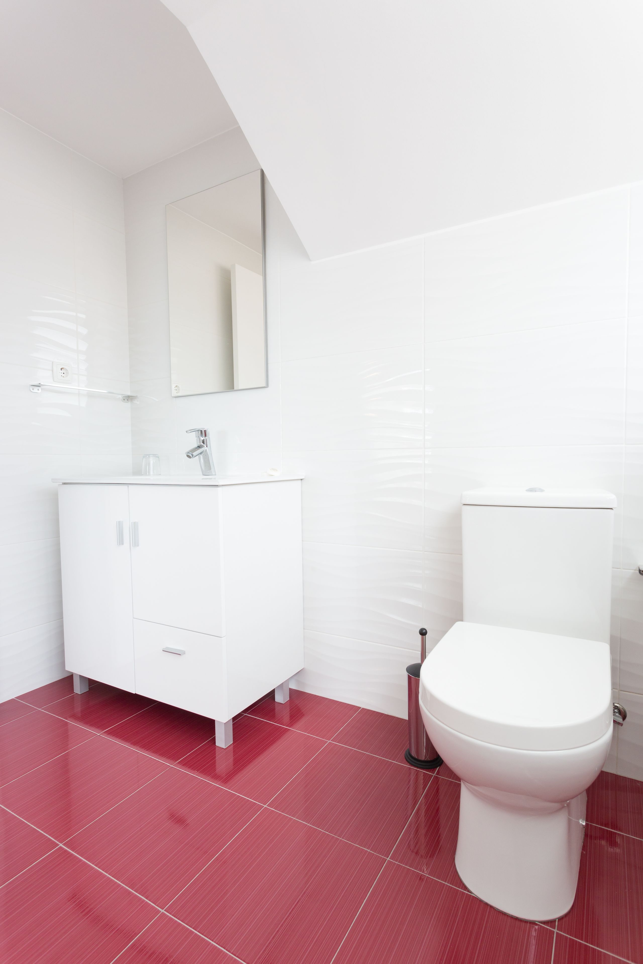 A modern bathroom with a white vanity, a toilet, and a mirror.