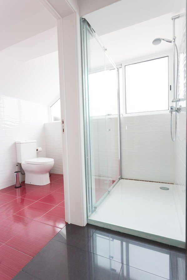 A modern bathroom with a glass shower enclosure, a white toilet, and red-tiled flooring. - 35th Atlantic View (Lajes do Pico)
