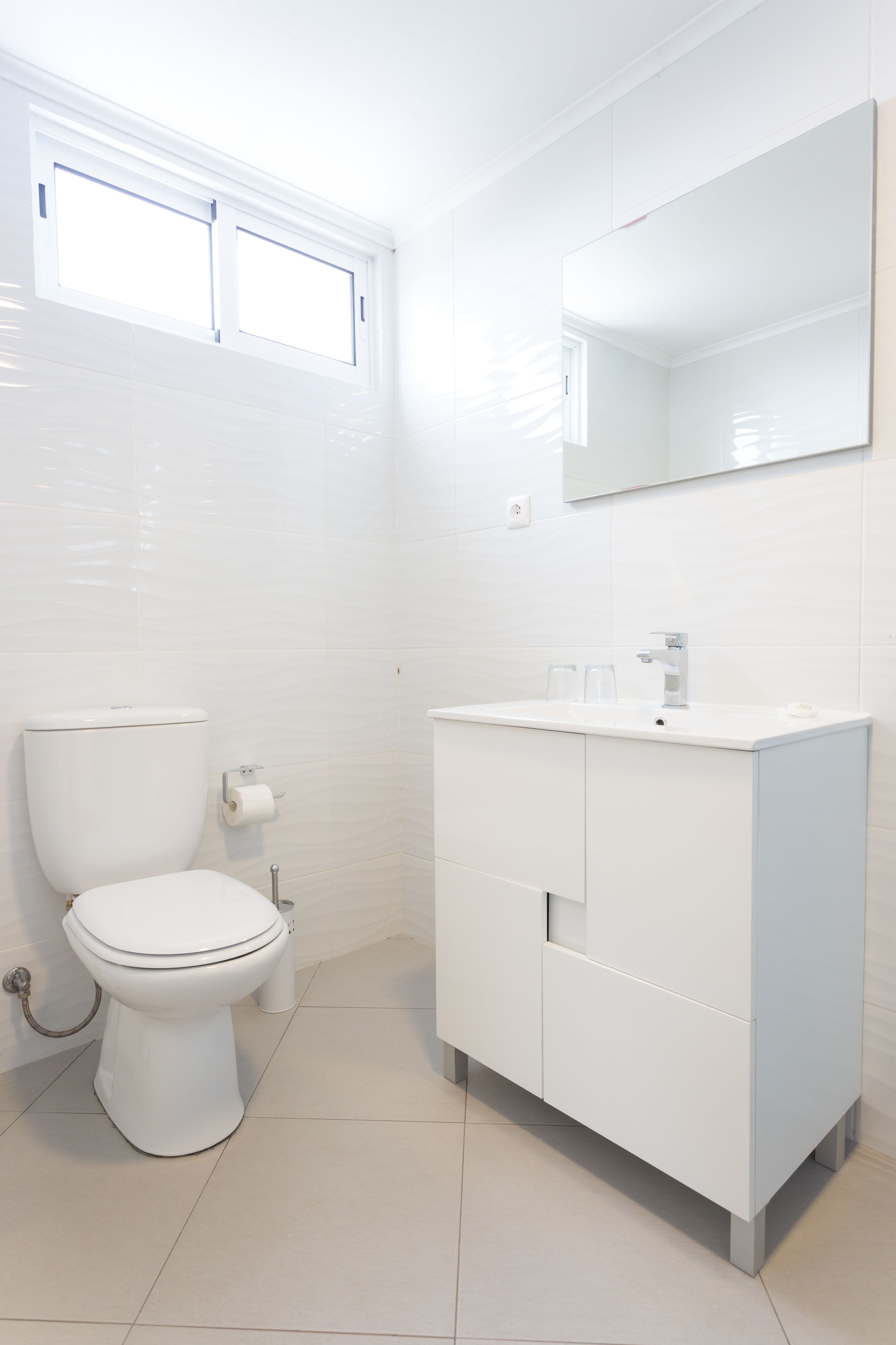 A modern bathroom with a toilet, sink, and mirror.