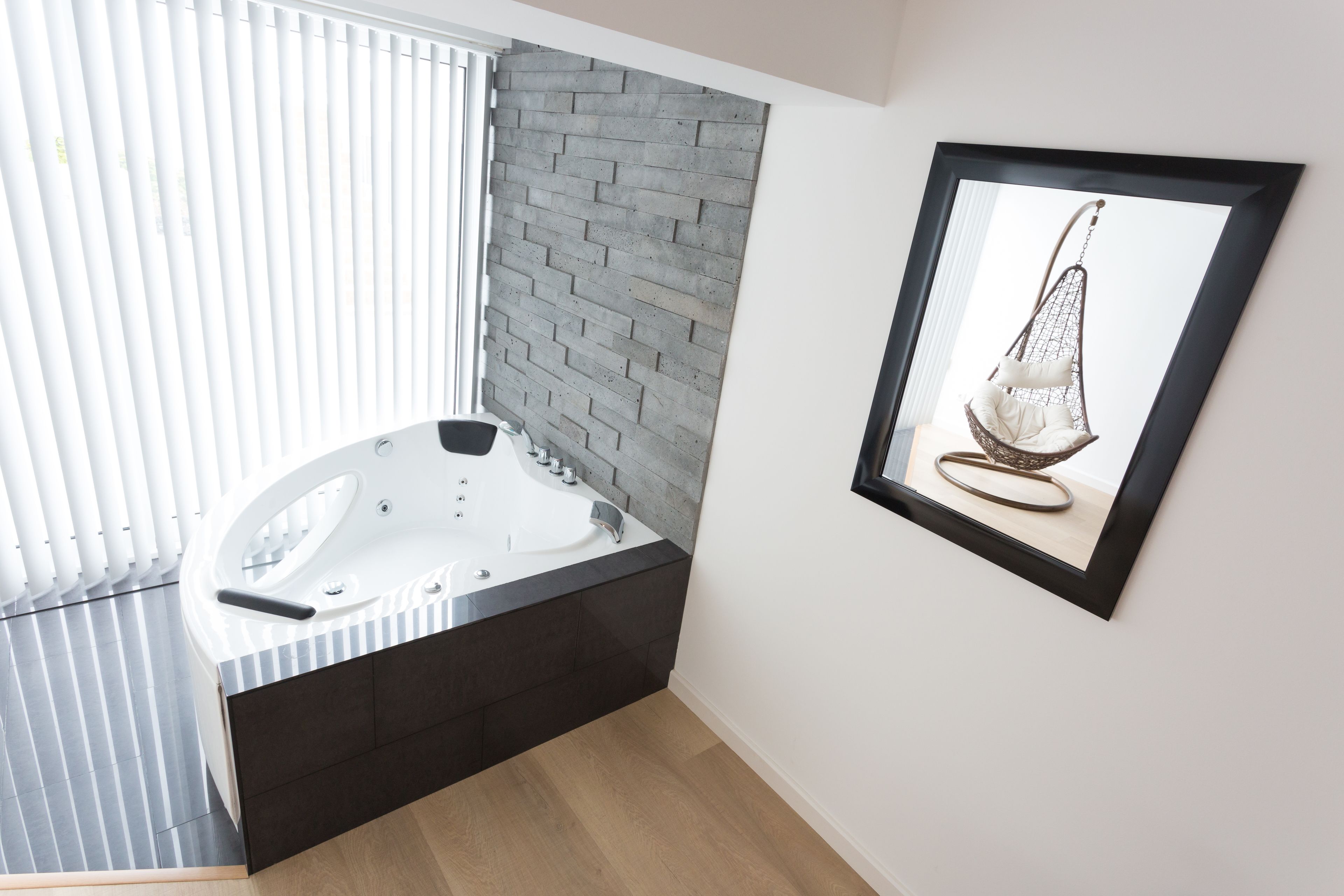 Une salle de bain moderne avec une baignoire sur pieds, un mur d’accent en briques et une œuvre d’art encadrée accrochée au mur.