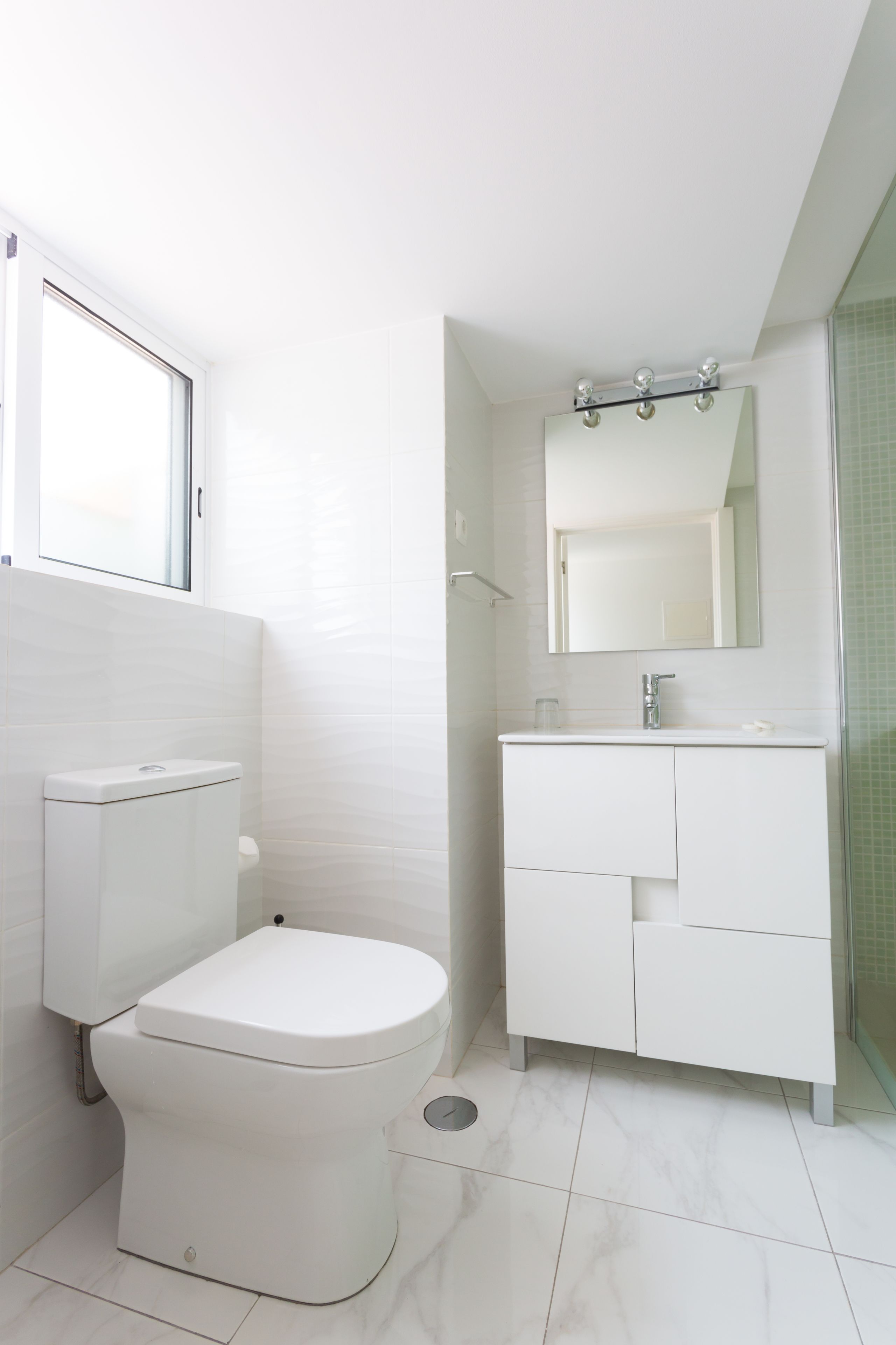 A modern bathroom with a toilet, a sink, and a mirror.