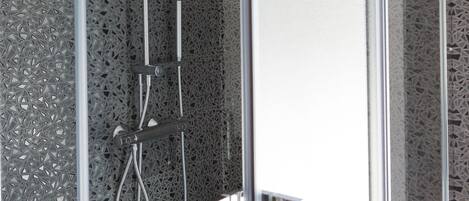 A modern shower enclosure with a glass door and a textured wall.
