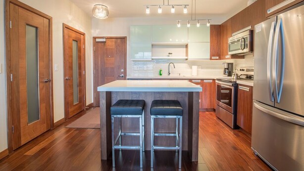 Una cucina moderna con mobili in legno, elettrodomestici in acciaio inossidabile e un'isola centrale con sgabelli.