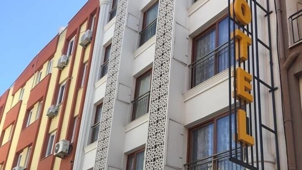 Un hotel con un letrero llamativo que dice "ÖZGUR HOTEL" y un logo con un sol y una estrella.
