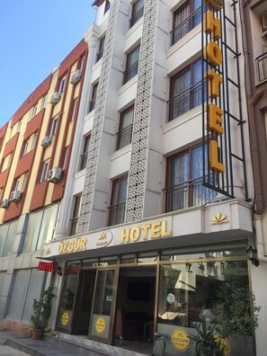Un hotel con un letrero llamativo que dice "ÖZGUR HOTEL" y un logo con un sol y una estrella.