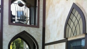 A building with a courtyard filled with colorful flowers, a balcony with a railing, and a window with a decorative grille. - Abbey Archway Inn (Fairbanks)