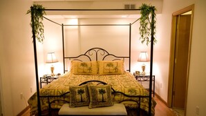 A four-poster bed with a yellow bedspread and palm tree pillows, flanked by two bedside lamps. - Abbey Archway Inn (Fairbanks)