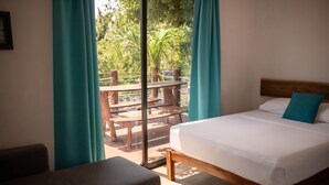 A bedroom with a bed, a wooden headboard, and a view of an outdoor patio with a table and chairs. - Hotel Ade (Bacalar)