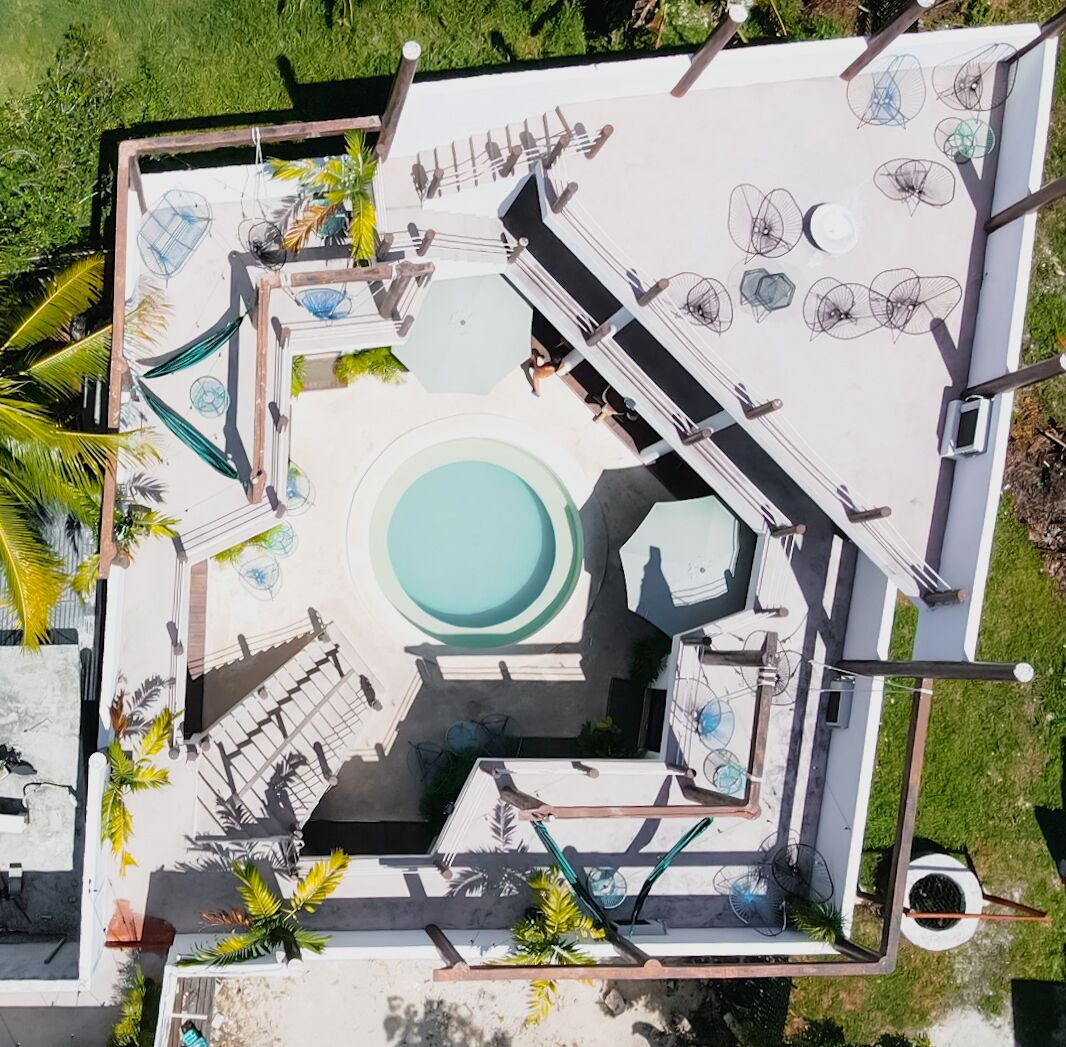 An aerial view of a rooftop pool area with a central swimming pool, lounge chairs, and umbrellas.