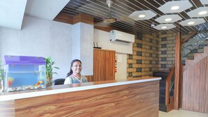 A reception desk with a wooden finish, a fish tank, and a staircase with wooden railings. - Hotel Plaza Executive Kurla (Mumbai)