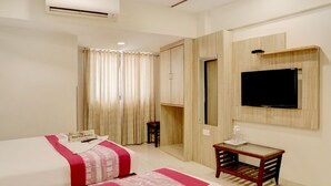 A hotel room with a bed, a desk, a television, and a mirror. - Hotel Plaza Executive Kurla (Mumbai)