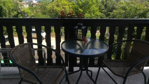 A balcony with wicker chairs and a glass table, overlooking a scenic view of the sea and greenery. - HOLLY - Quiet guest house with seaview and a pool (Balchik)
