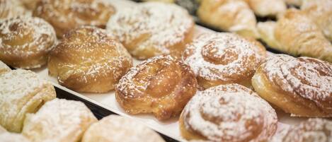 A display of various pastries, including doughnuts and pastries dusted with powdered sugar.