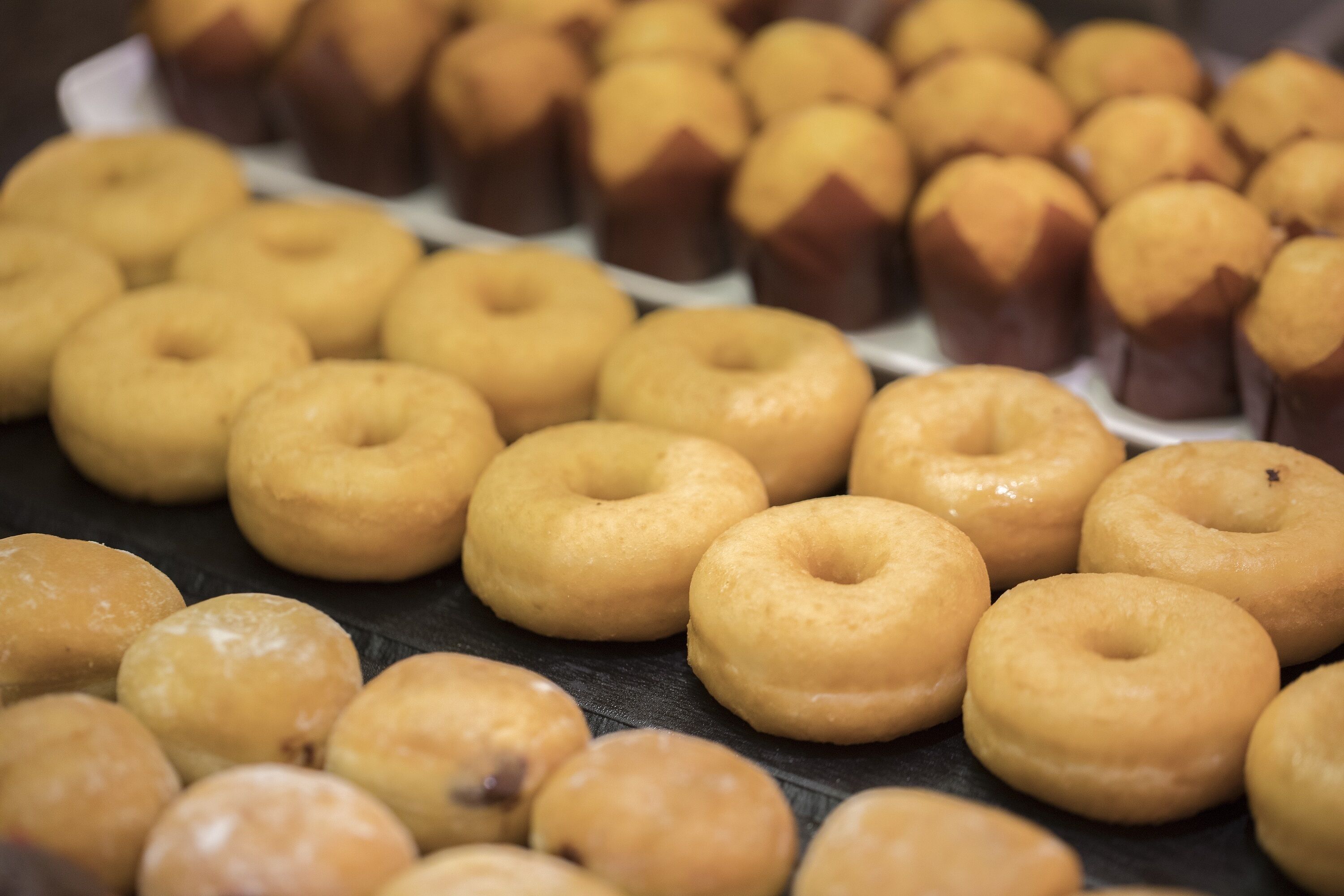A display of various donuts, including glazed and chocolate varieties, arranged on a tray.