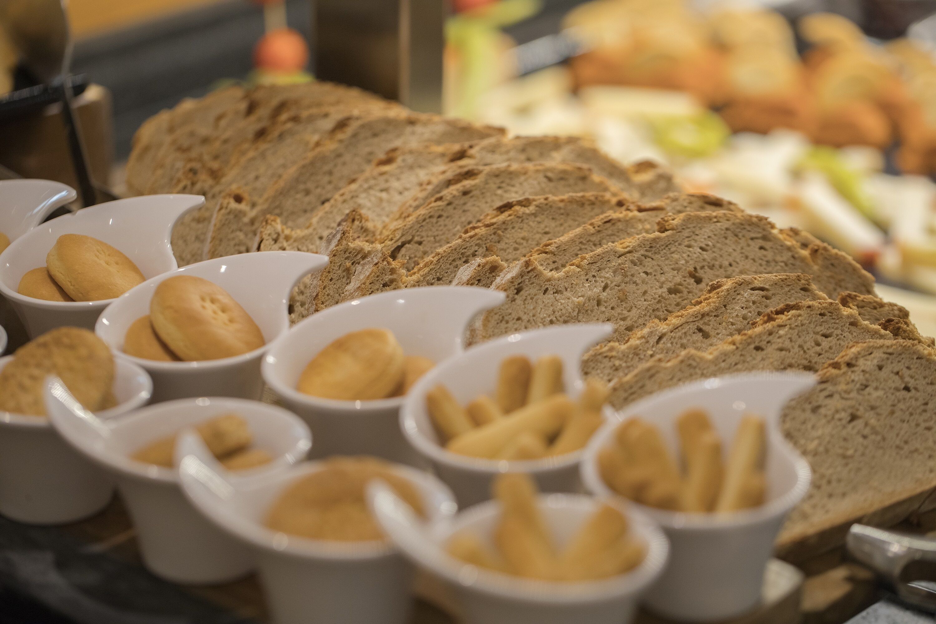 A variety of breads and pastries displayed in white bowls.