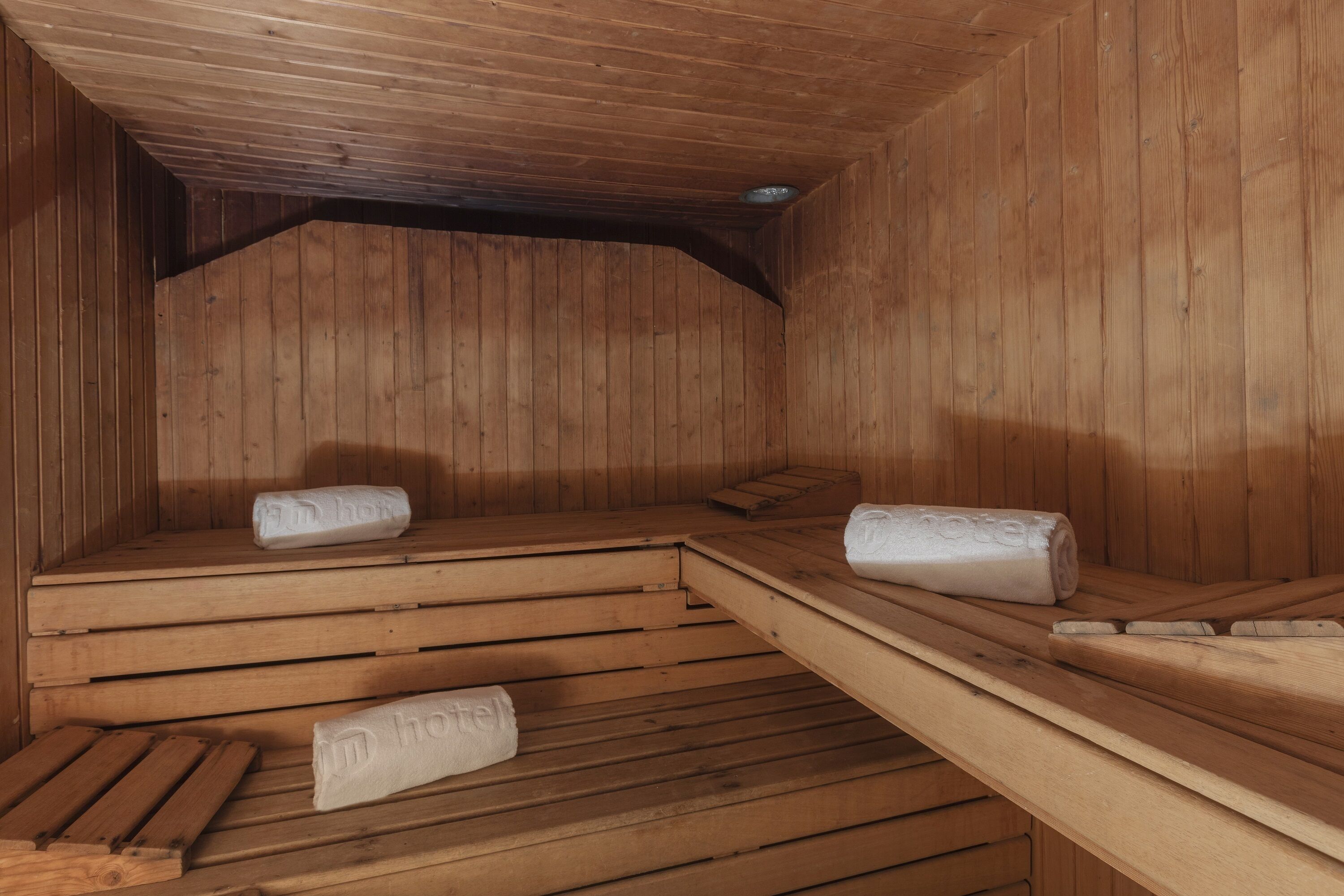 Una sauna con bancos de madera y toallas sobre ellos.