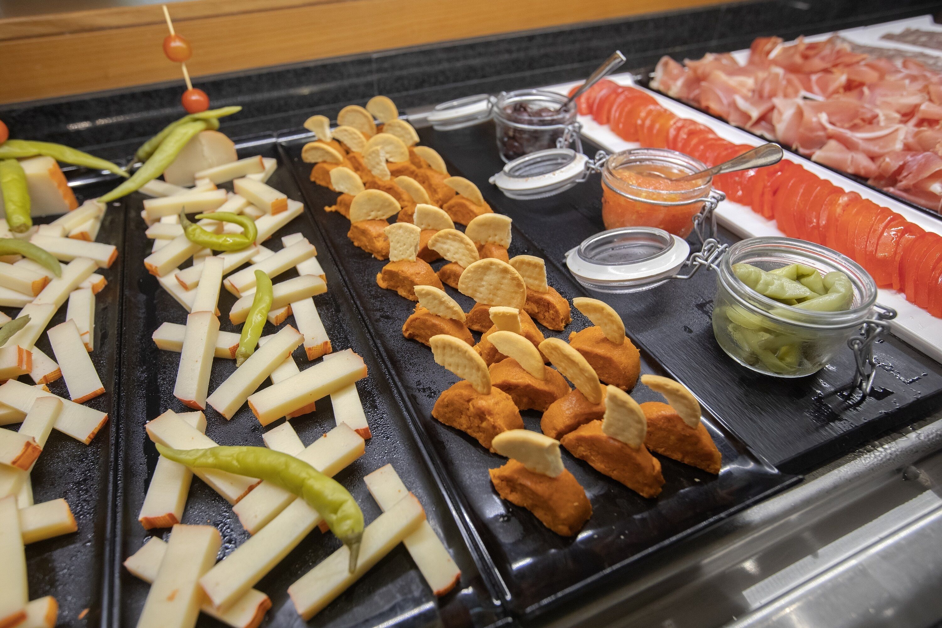 Ein reichhaltiges Buffet mit verschiedenen Speisen, darunter Apfelscheiben, Käse, Cracker und Aufschnitt.