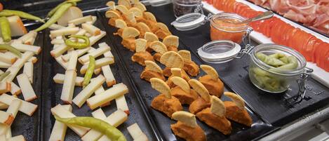 Ein reichhaltiges Buffet mit verschiedenen Speisen, darunter Apfelscheiben, Käse, Cracker und Aufschnitt.