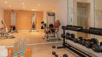 Ein Fitnessraum mit Trainingsgeräten, Kurzhanteln und Wasserflaschen.
