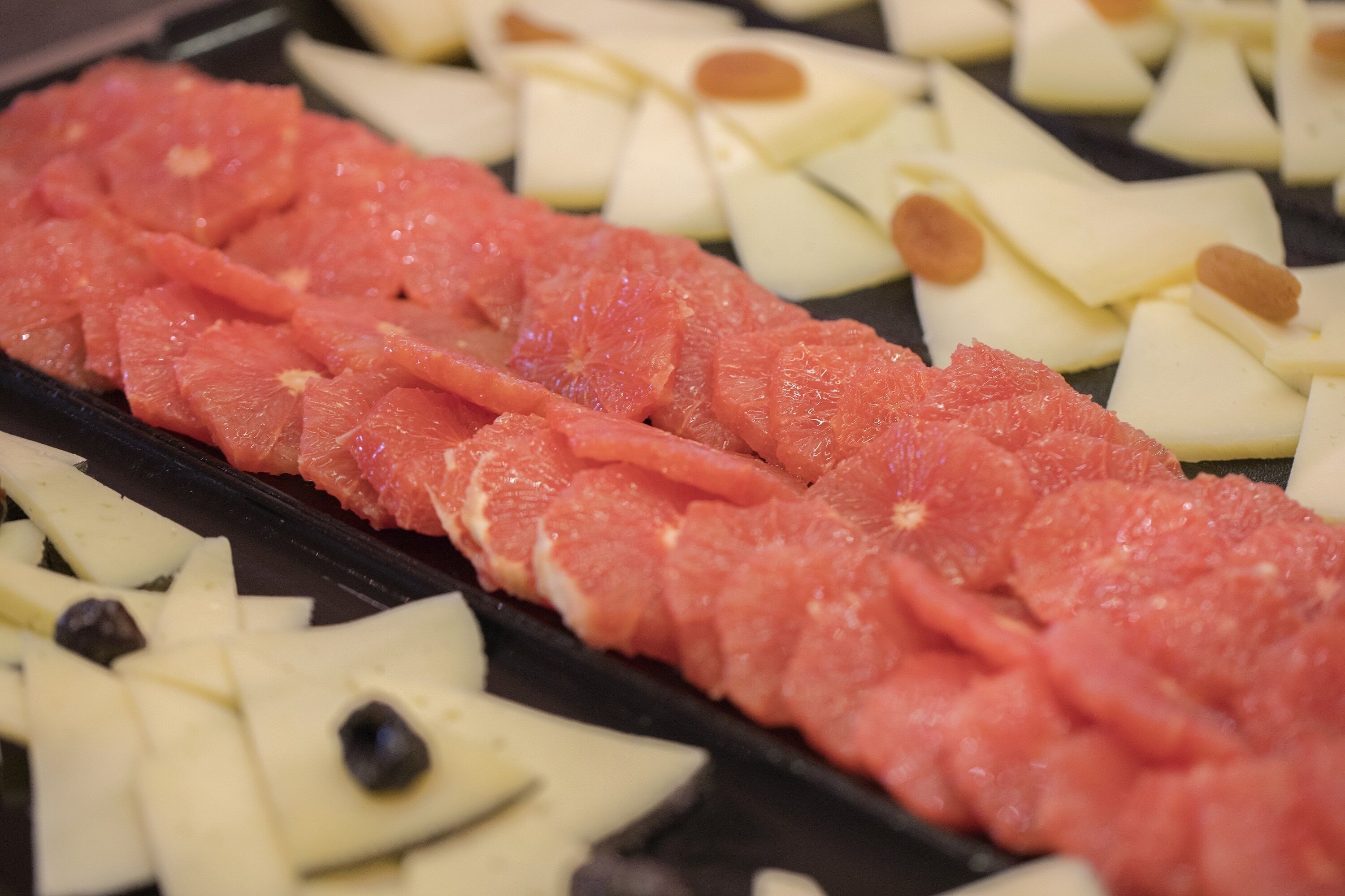 Una bandeja con carne roja en rodajas, queso blanco y almendras.