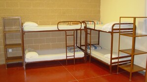 Habitación con literas, suelo de baldosas y pared de ladrillo.