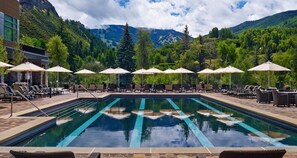 A swimming pool with lounge chairs and umbrellas, surrounded by trees and mountains. - Charlie's Slopeside: Remodeled, Wraparound Deck, Gondola, Resort Amenities, Pool + Hot Tubs (Avon)