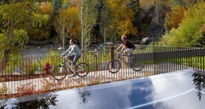 A pedestrian bridge with a metal railing, a red fire hydrant, and a bicycle path. - Charlie's Slopeside: Remodeled, Wraparound Deck, Gondola, Resort Amenities, Pool + Hot Tubs (Avon)