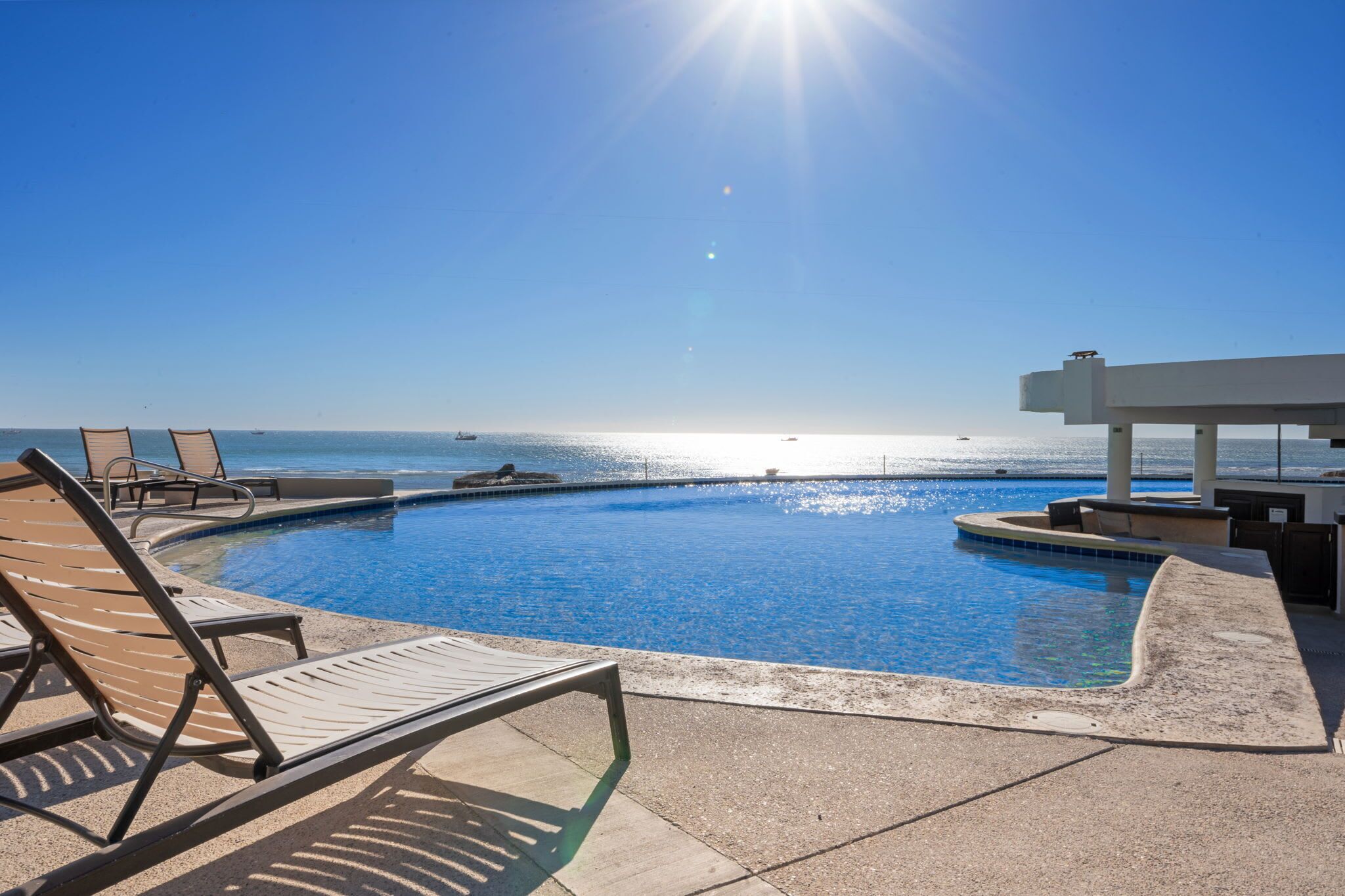Una piscina con sedie a sdraio e vista sull'oceano.