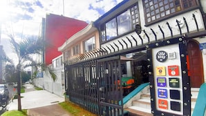 Un bâtiment doté d’une entrée sécurisée par un portail, d’un escalier et de nombreux panneaux indiquant différents services, tels qu’une auberge de jeunesse, un bar et un restaurant.