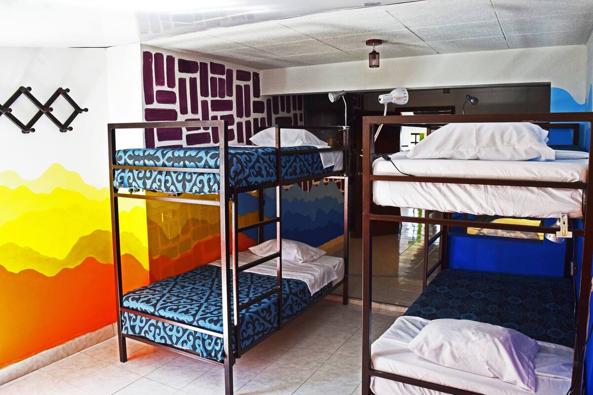 Ein Schlafsaalzimmer mit Etagenbetten, Wandgemälde und Deckenventilator.