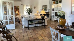 A spacious living area with a fireplace, a dining table, and a sofa. - Beautiful stone house in olive grove, great pool area and garden, panoramic view (Callas)