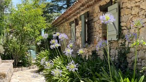 Un bâtiment en pierre, doté d’un toit recouvert de tuiles et d’un chemin en pierre menant à l’entrée.