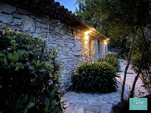 Un edificio de piedra con un camino de piedra que lo lleva hasta él, rodeado de follaje.