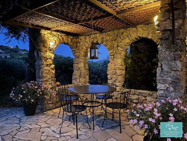 Un patio al aire libre con paredes de piedra, una mesa redonda y sillas.