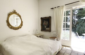 A bedroom with a bed, a bedside table, a chair, a mirror, and a window with curtains. - Beautiful stone house in olive grove, great pool area and garden, panoramic view (Callas)
