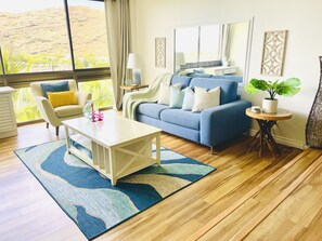 Relax in this stylish living room with a blue sofa, coffee table, and side table, surrounded by a hilly view.