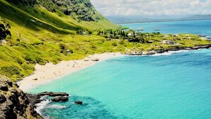 A coastal landscape with a beach, clear turquoise waters, and lush green hills. - Breathtaking Ocean Views! Peaceful Retreat/No Resort Fees. 
 (Honolulu)