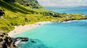 Overlooking a serene beach with a rocky shoreline and lush hillside.