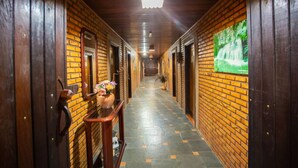 Un corridoio con pareti in mattoni, porte in legno e pavimento piastrellato.