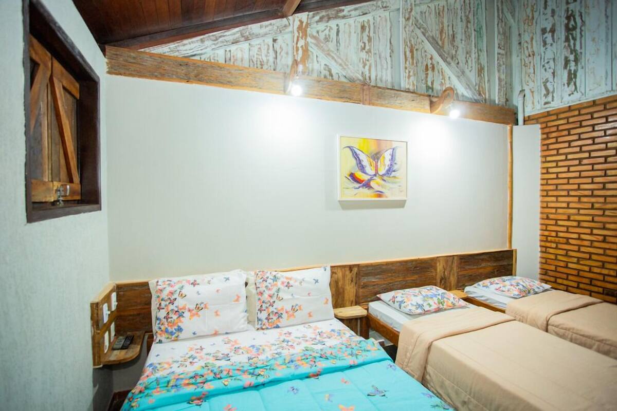 A room with a bed, two bedside tables, a wooden headboard, a brick wall, and a ceiling with exposed beams.