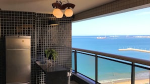 A kitchen with a view of the sea, a refrigerator, a potted plant, and a bar area. - Landscape Beira Mar, Lindo, Luxo, Vista mar (Fortaleza)