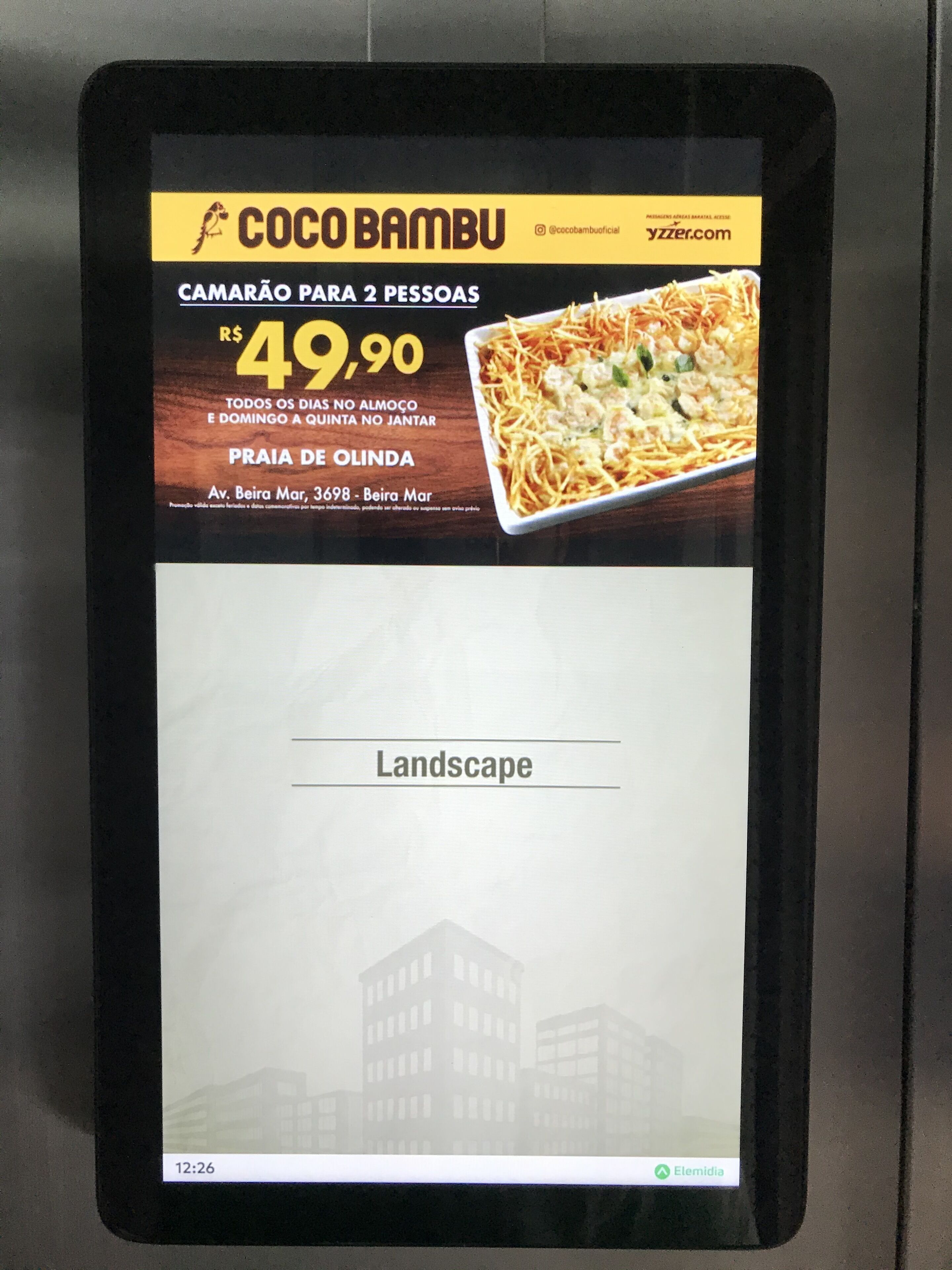 A digital menu board advertising a meal for two at COCOBAMBU for R$ 49,90, located at Av. Beira Mar, 3698 - Beira Mar.