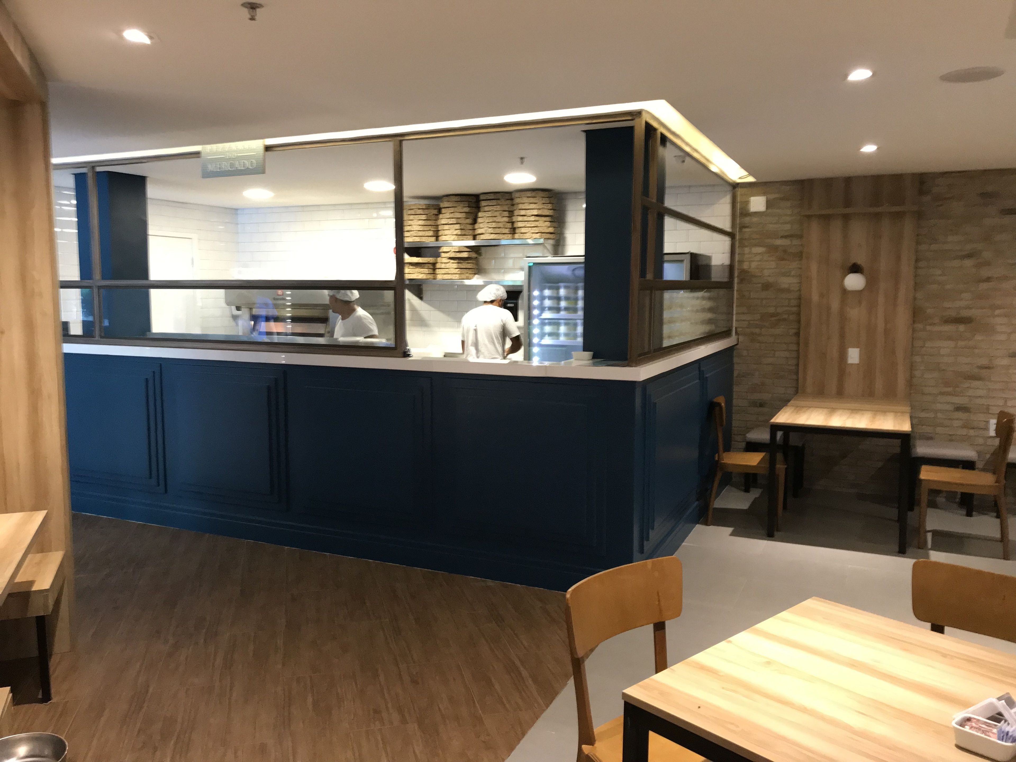 A restaurant with a blue counter, wooden tables, and chairs.