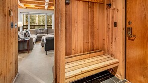 Een houten interieur met een bank, een deur en uitzicht op een zithoek met een bank en een lamp.