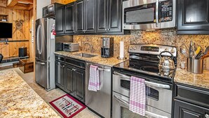Een moderne keuken met roestvrijstalen apparatuur, granieten aanrechtbladen en houten kastjes.