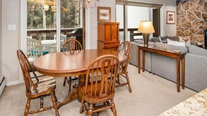 Een eetruimte met een houten tafel en stoelen, een kroonluchter en een stenen open haard.