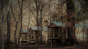 A rustic cabin with a wooden deck and a staircase leading to a porch. - Bowman's Landing Spring House on the Santa Fe River (Fort White)