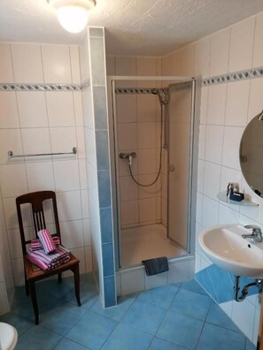 A bathroom with a shower, a sink, and a chair. - Gästehaus Burg Molbach (Kreuzau)