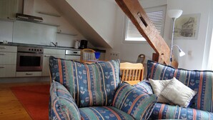 Un salon confortable avec un canapé, une table à manger en bois et un coin cuisine équipé d’une cuisinière et de placards.